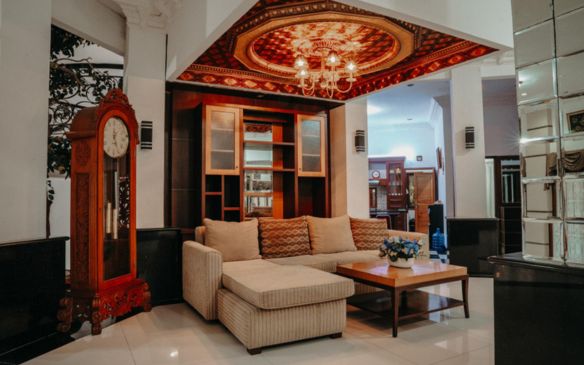 A stylish living room featuring a large chandelier and an elegant clock, designed by an architect and interior designer in Kolkata.